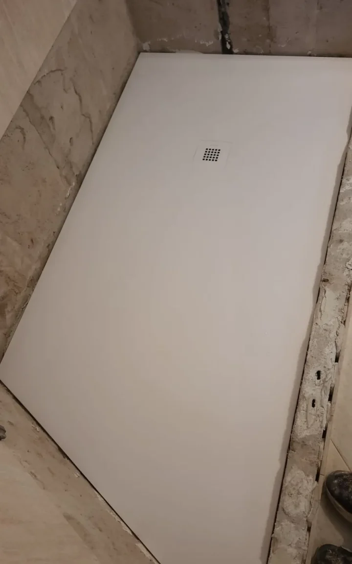 Plato de ducha blanco recién instalado a ras de suelo