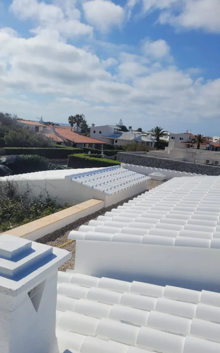 Cubierta de teja blanca y chimenea pintada en una urbanización costera de Menorca